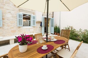 A wooden table set for two with a vase of flowers, a teapot, and glasses.