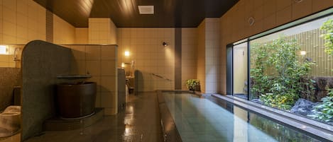 Un spa moderno con una amplia piscina interior, un banco de piedra y vistas a la vegetación a través de un gran ventanal.