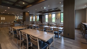A spacious dining area with multiple tables and chairs, large windows, and a modern ceiling design. - Hotel Route-Inn Kanuma Inter (Kanuma)