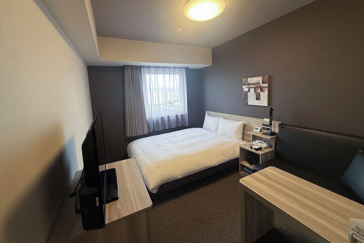 Une chambre d’hôtel équipée d’un lit, d’une table de chevet, d’un bureau et d’un téléviseur.