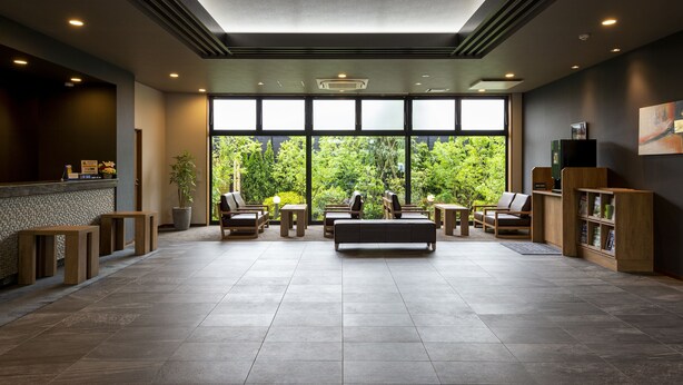 A spacious lobby with a reception desk, seating area, and large windows offering a view of greenery. - Hotel Route-Inn Kanuma Inter (Kanuma)