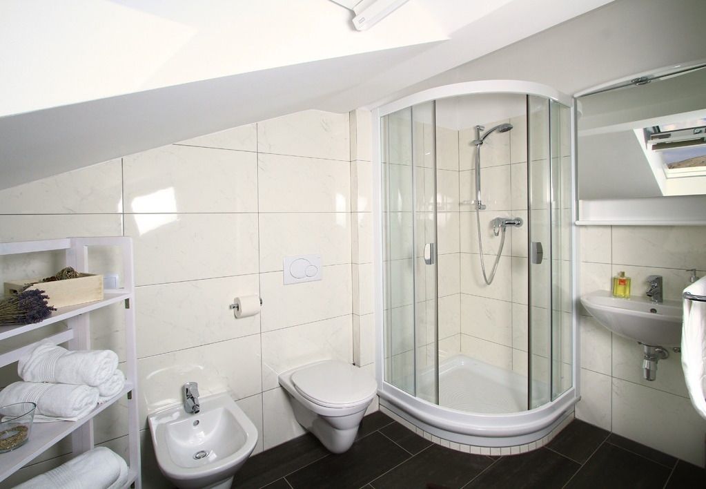 Ein modernes Badezimmer mit einer Duschkabine, einem weißen Waschbecken und einer Toilette.