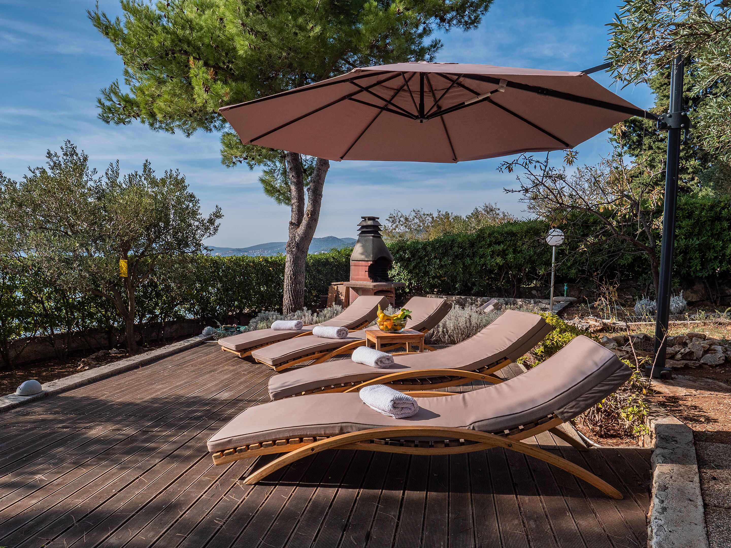 A deck with lounge chairs and a large umbrella.