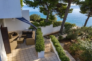 Una terraza con mobiliario exterior, vistas al mar y un jardín ajardinado.