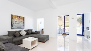 A modern living room with a grey sectional sofa, a white coffee table, and a painting of Buddha on the wall. - Casa Sirena (Santa Cruz de Tenerife)