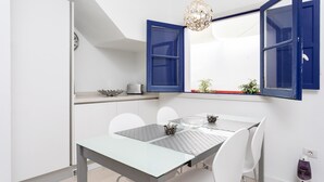 A dining area with a glass table, white chairs, and blue-framed windows. - Casa Sirena (Santa Cruz de Tenerife)