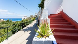A staircase with red steps leading up to a white building, surrounded by greenery and overlooking a coastal view. - Casa Sirena (Santa Cruz de Tenerife)