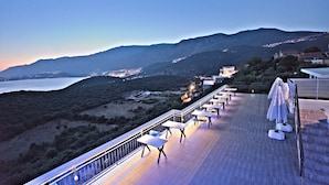 A terrace with tables and chairs overlooking a coastal landscape with mountains in the background. - Stone Hill Kas (Kas)