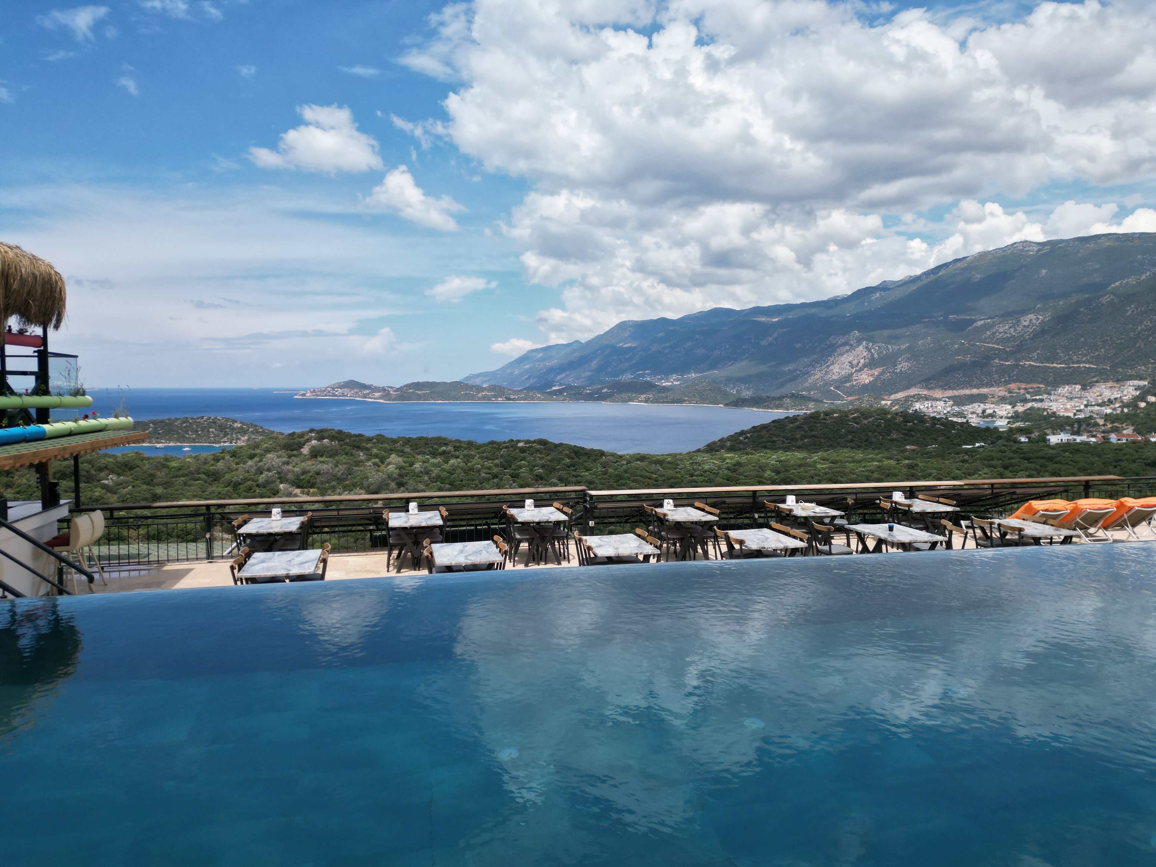Une piscine à débordement offrant une vue sur la mer et les montagnes.