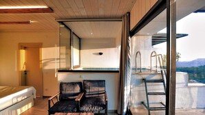 A modern room with a bed, two chairs, a small table, and a balcony with a view of the mountains. - Stone Hill Kas (Kas)