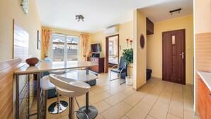 A modern kitchen with a dining area, a large window, and a door leading to another room. - Apartamenty Sun & Snow Bursztynowy (Wladyslawowo)