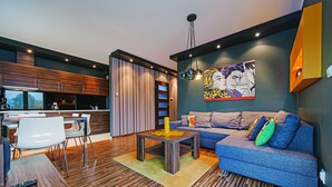 A modern living room with a sofa, coffee table, and dining area. - Apartamenty Sun & Snow Bursztynowy (Wladyslawowo)