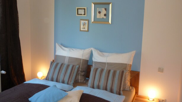 A bedroom with two beds, striped pillows, and framed pictures on the wall.