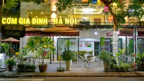 Un café amb terrassa, plantes en testos i un cartell de neó.