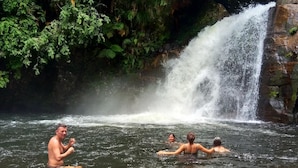 Ein Wasserfall in einer natürlichen Umgebung, mit Menschen im Wasser.