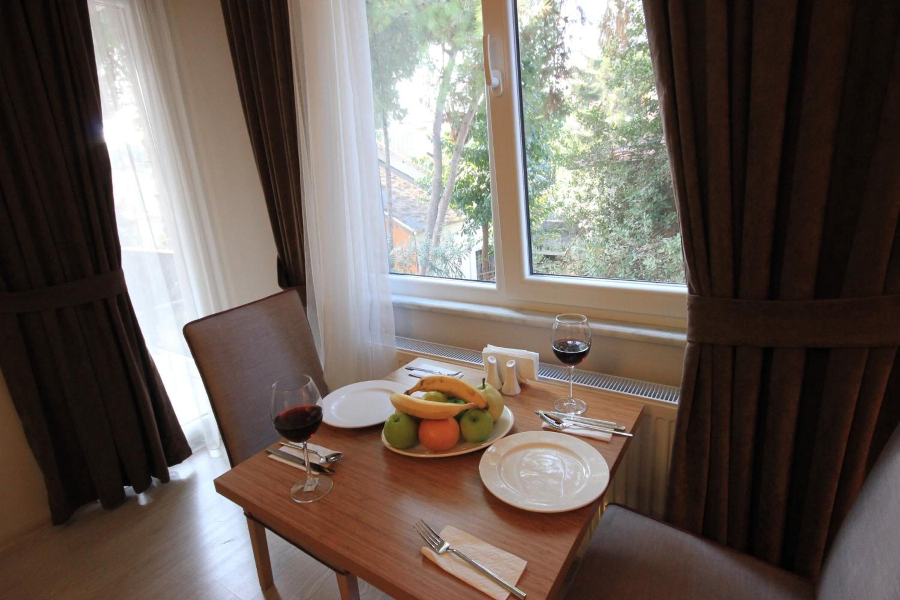 A dining table with plates, a bowl of fruit, wine glasses, and cutlery.