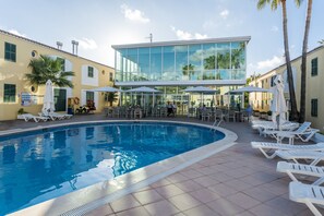 Una piscina al aire libre, sombrillas, tumbonas