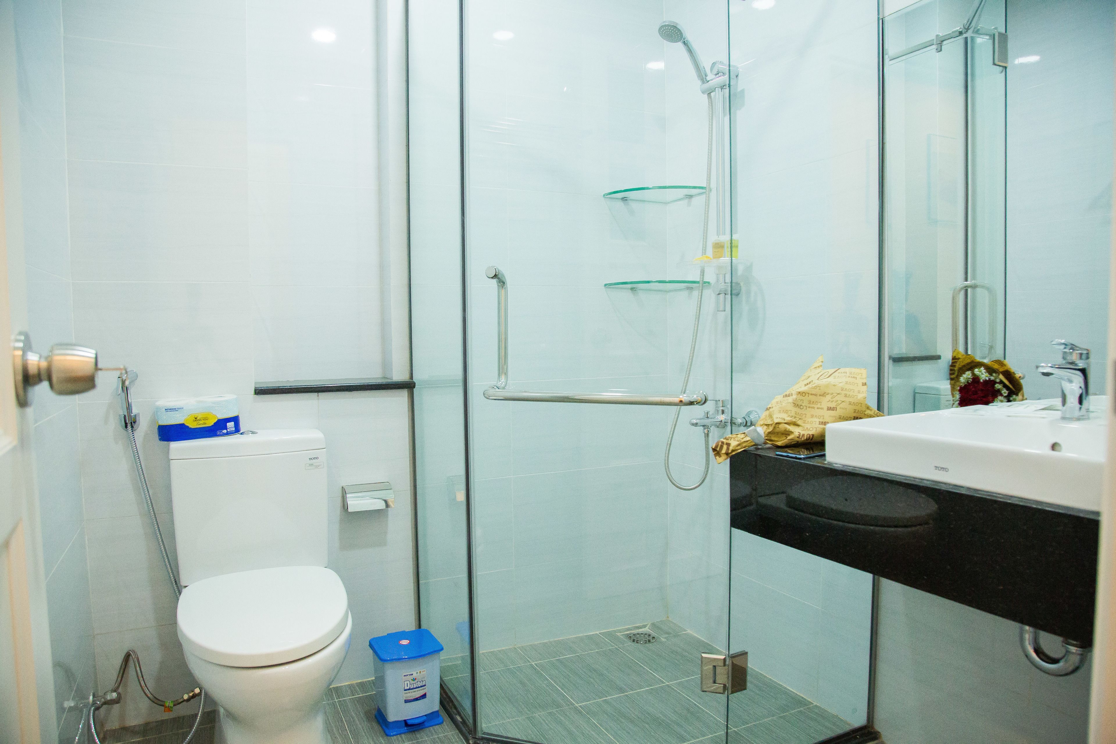 A modern bathroom with a toilet, glass shower enclosure, and a sink with a mirror.