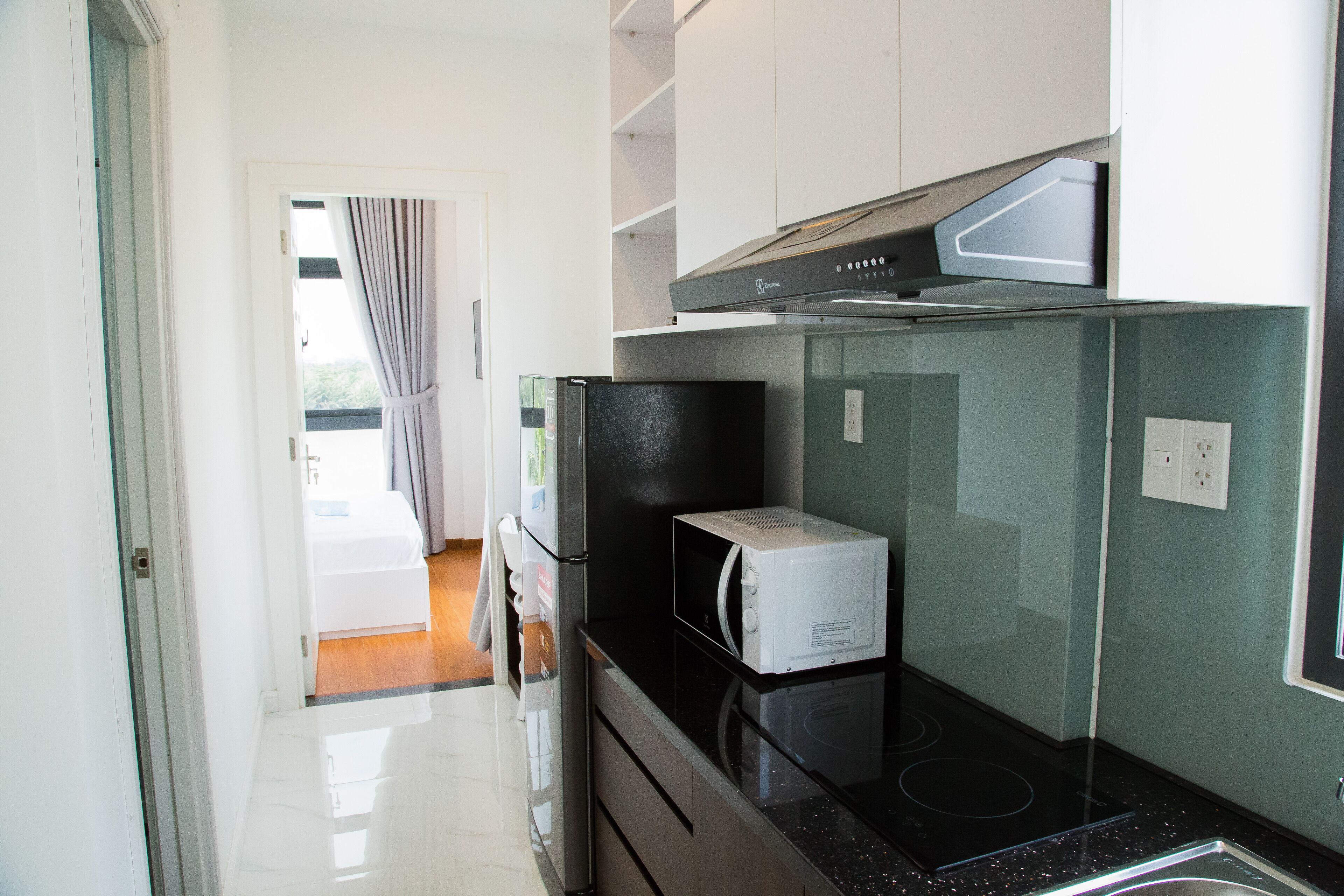 A modern kitchen with a black countertop, white cabinets, and a microwave.