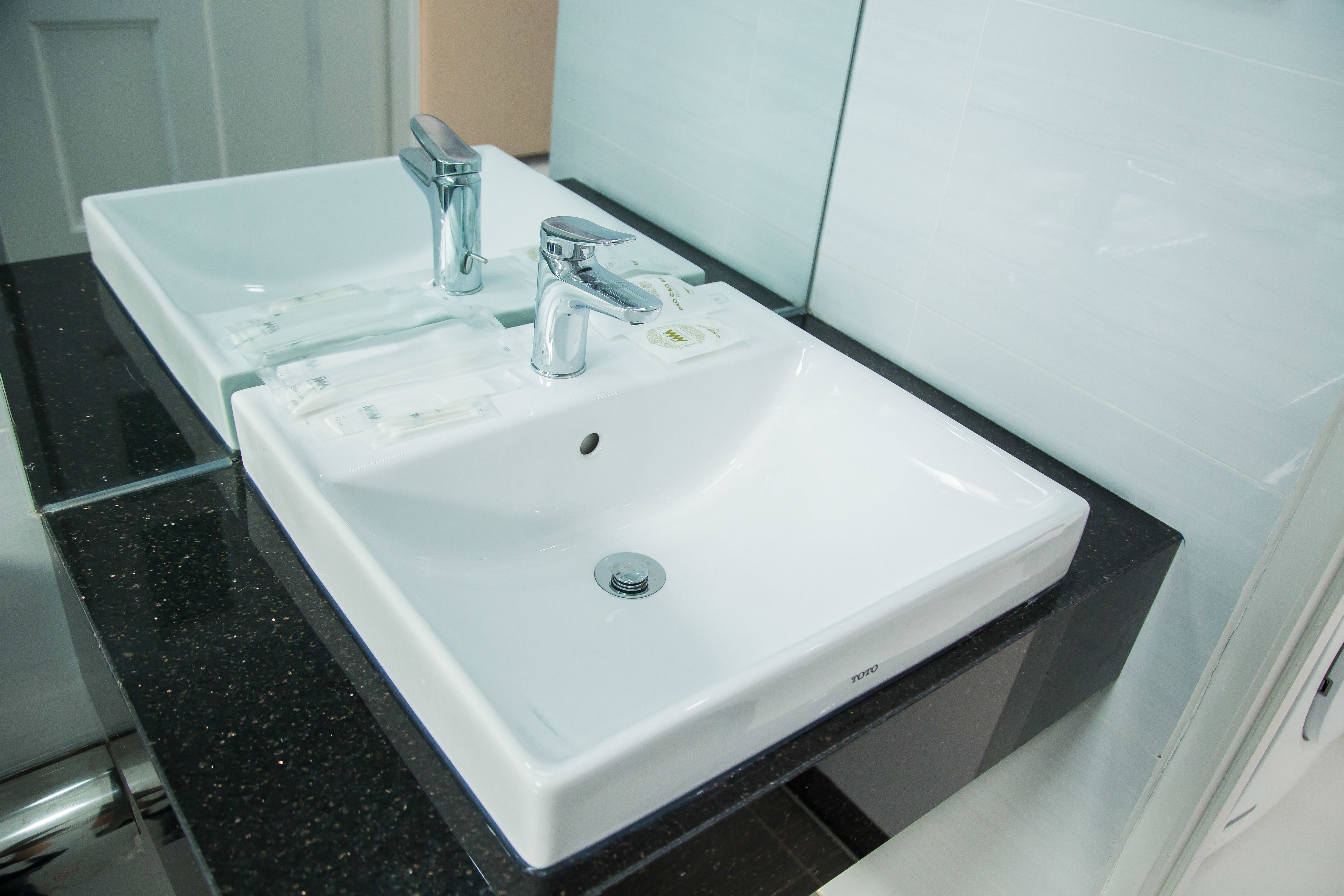 Un baño con dos lavamanos, cada uno con un grifo moderno, y un espejo encima.