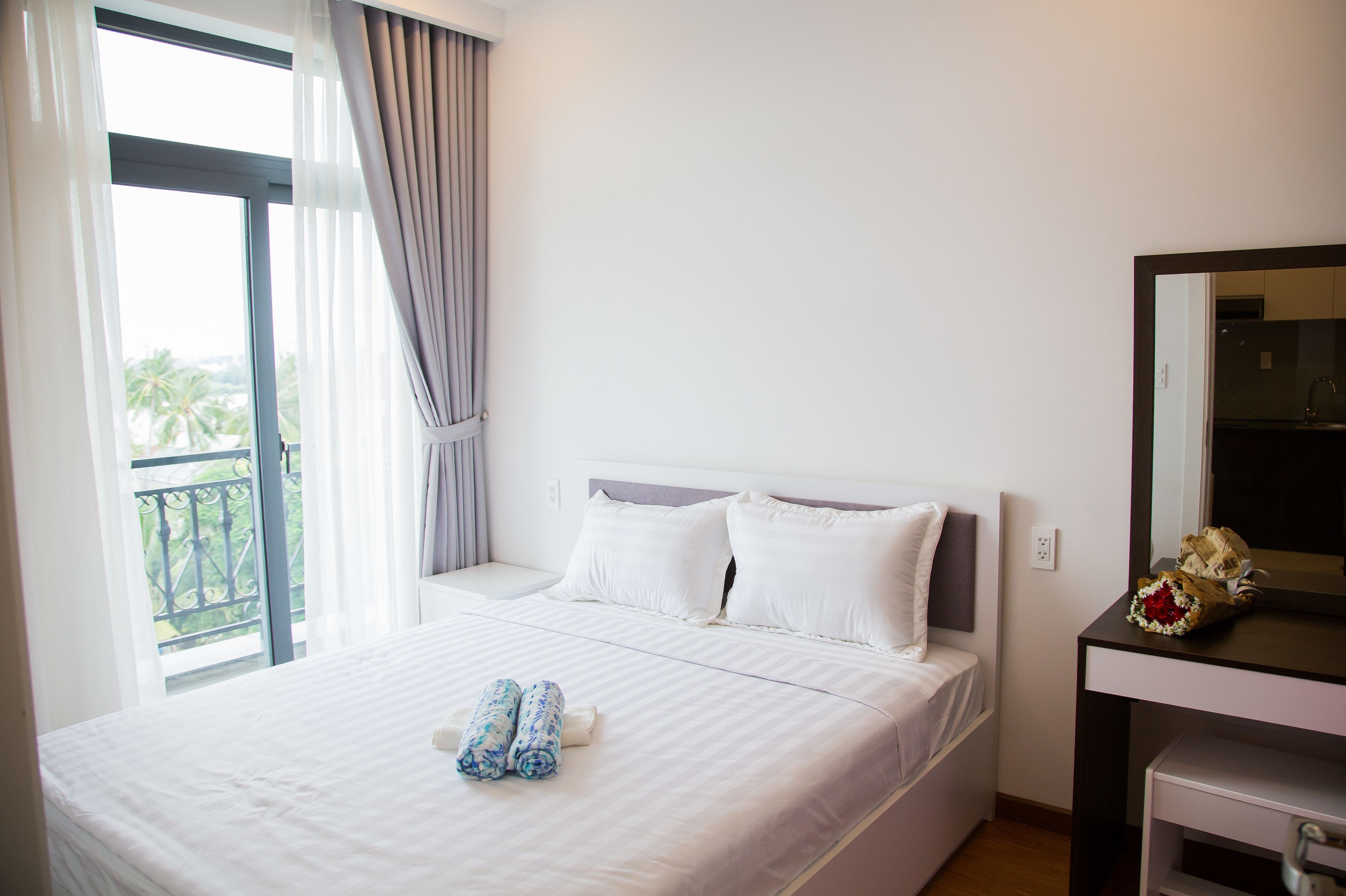 Ein Hotelzimmer mit einem Bett, einem Nachttisch, einem Spiegel und Blick ins Freie.