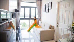Ein modernes Hotelzimmer mit großem Fenster, einer Couch, einem Fernseher und einem Glastisch.