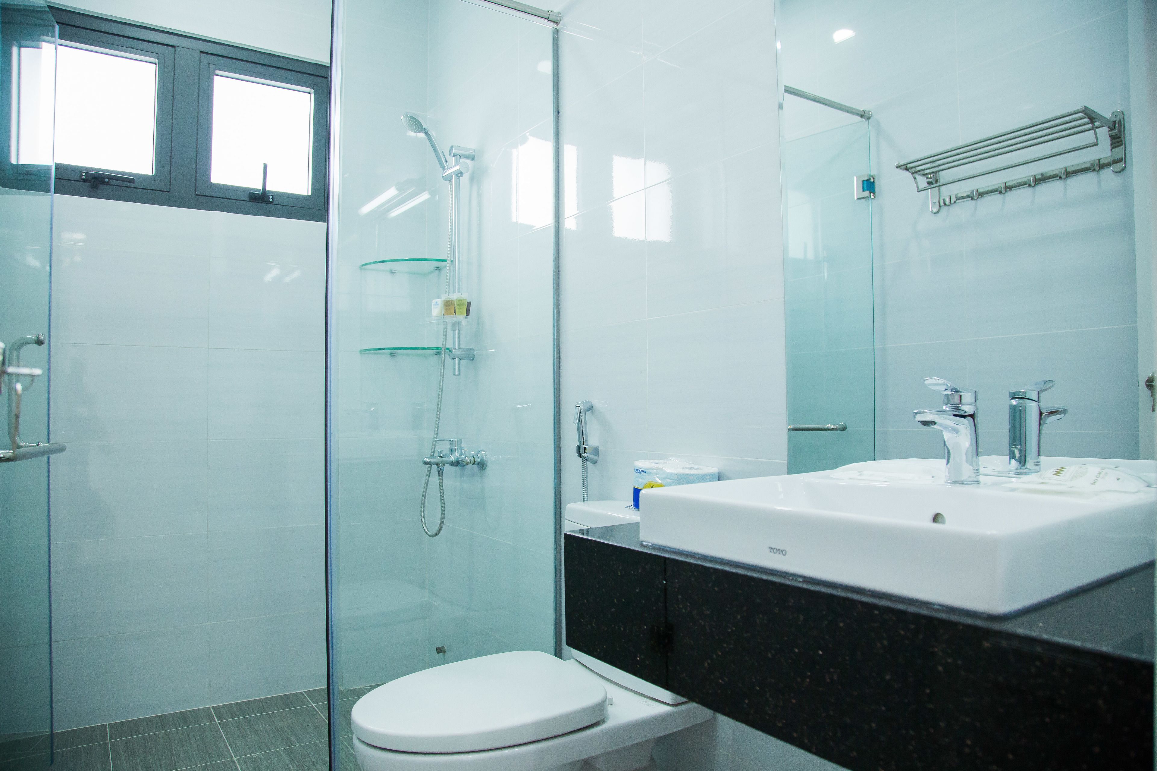 Un baño moderno con cabina de ducha de vidrio, inodoro blanco y un lavamanos grande con espejo arriba.