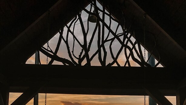 A wooden gazebo with a view of a sunset over a lake.