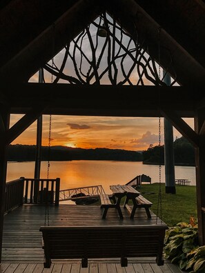 Un gazebo in legno con vista su un tramonto sul lago.