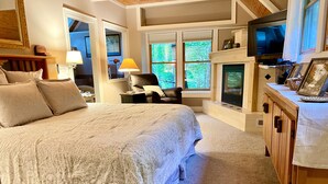 A spacious bedroom with a large bed, a television, and a fireplace.
