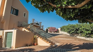 A building with a staircase leading to a balcony, a green door, and potted plants. - Villa Fantasia (Kefalonia)