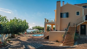 A two-story building with a pool, outdoor seating, and a staircase leading to the upper level. - Villa Fantasia (Kefalonia)