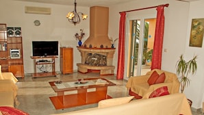 A living room with a fireplace, television, and seating area. - Villa Fantasia (Kefalonia)