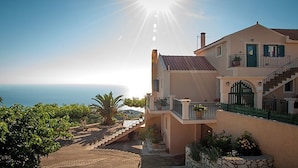 A coastal building with a staircase leading to a balcony, a view of the sea, and a clear sky. - Villa Fantasia (Kefalonia)