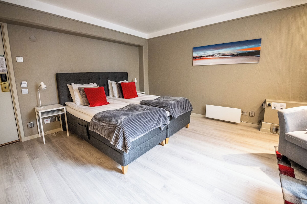 Une chambre à coucher moderne avec un lit, une table de chevet et un tableau au mur.