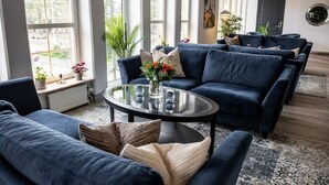 A modern living room with dark blue sofas, a glass coffee table, and a patterned rug. - Hotel Stensson (Eslöv)