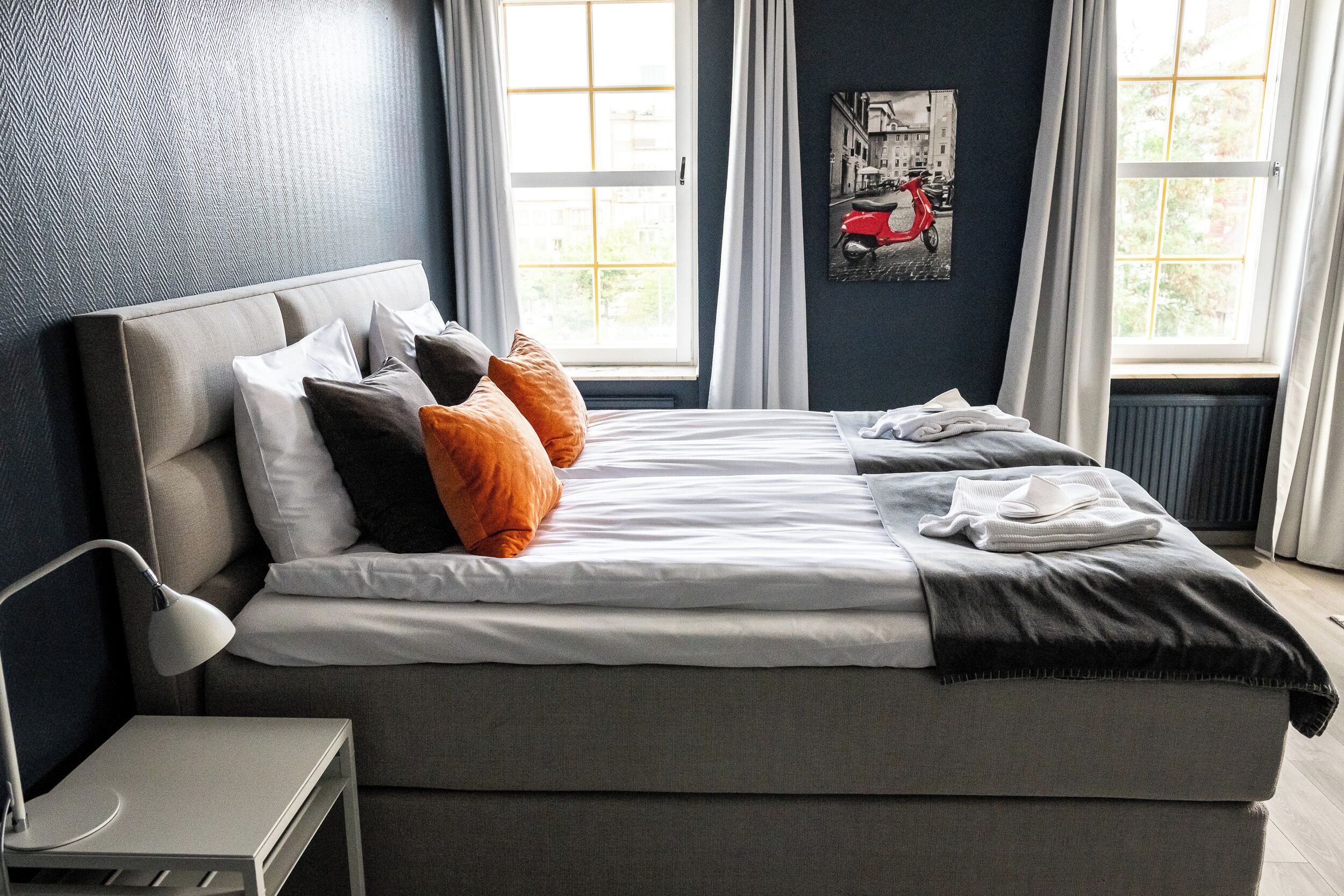 A modern bedroom with a large bed, a bedside table, and a window with curtains.