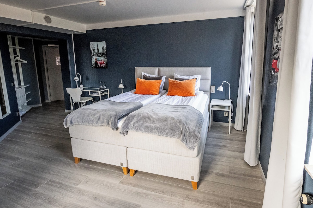 Une chambre moderne avec un grand lit, des tables de chevet, un bureau et une chaise.