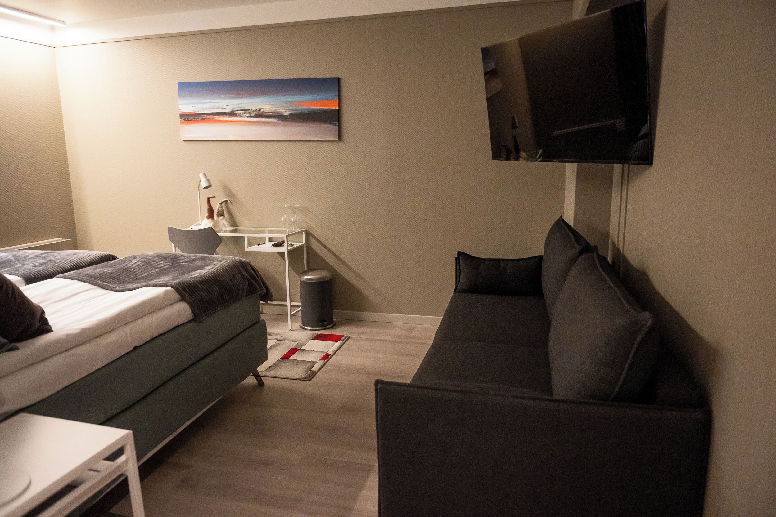 Une chambre d’hôtel moderne équipée d’un lit, d’un canapé, d’un bureau et d’une télévision.