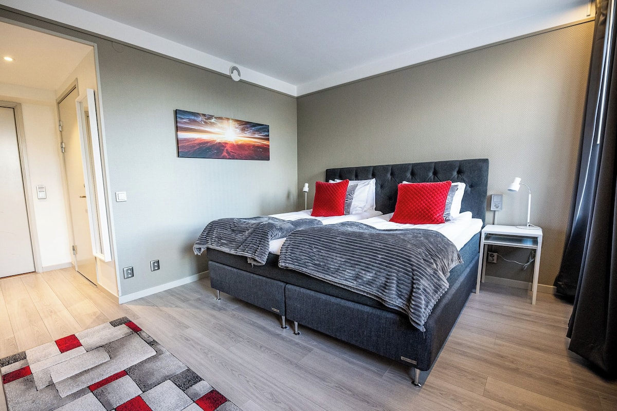 Une chambre à coucher moderne avec un grand lit, une table de chevet et une commode.