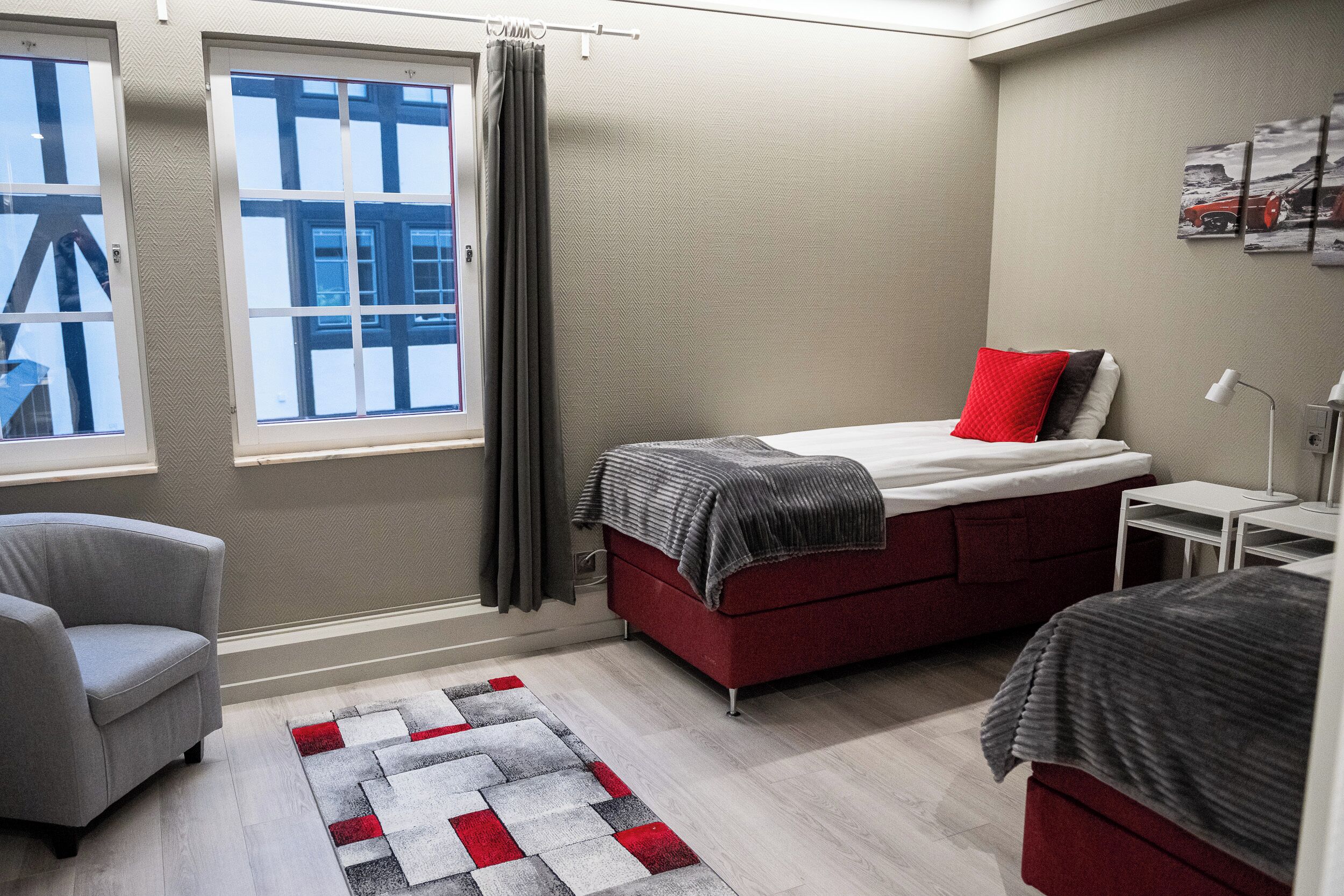 Una habitación de hotel moderna con una cama, una silla, un escritorio y una ventana con cortinas.