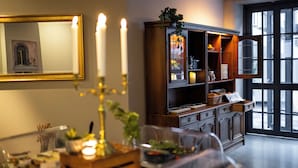 A dining area with a table set for a meal, a mirror with a golden frame, and a wooden cabinet with glass doors. - Hotel Stensson (Eslöv)