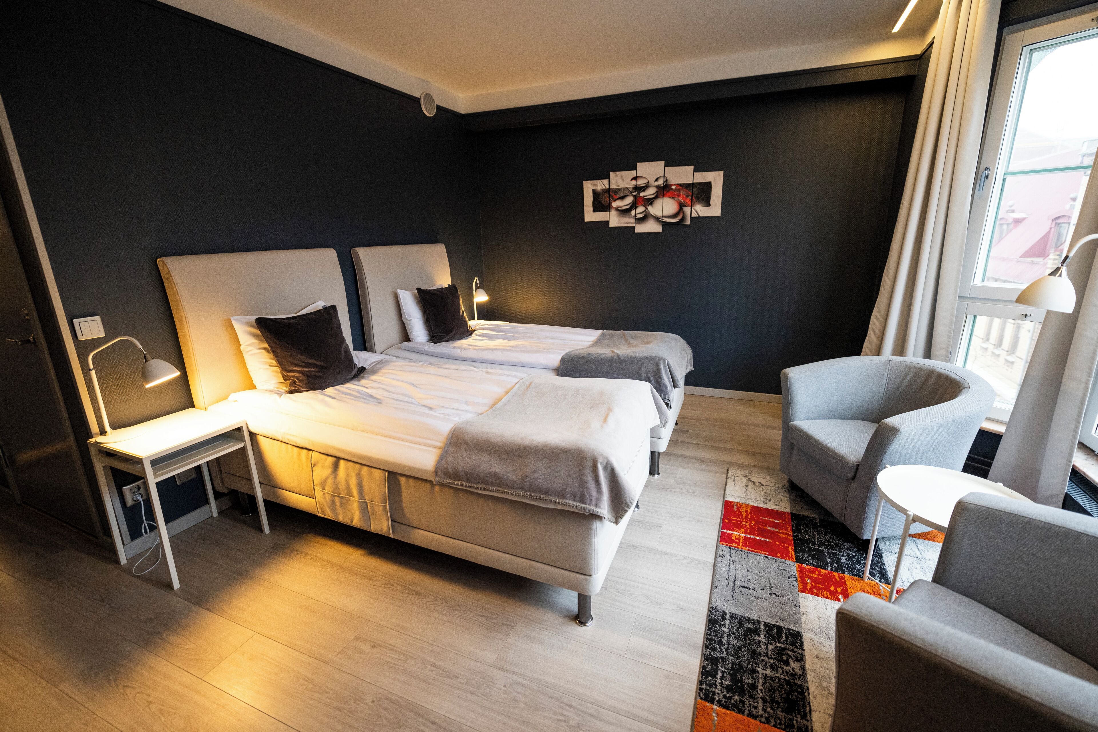 Een moderne hotelkamer met een groot bed, nachtkastjes, een stoel en een klein tafeltje.