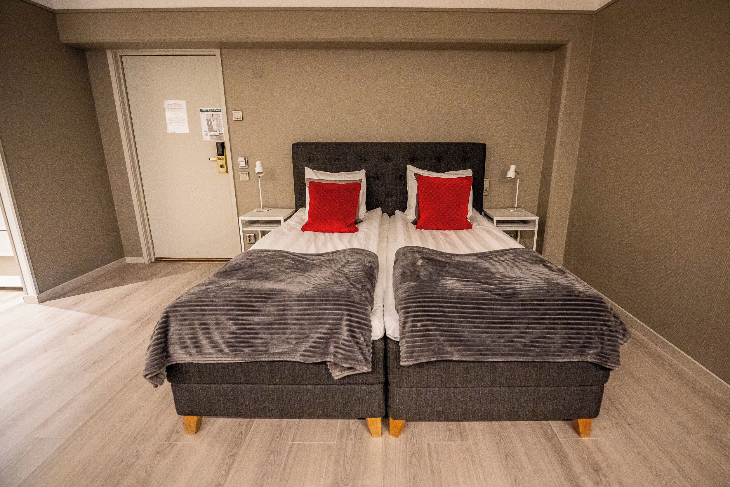 A double bed with a dark headboard, two nightstands with lamps, and a door with a lock.