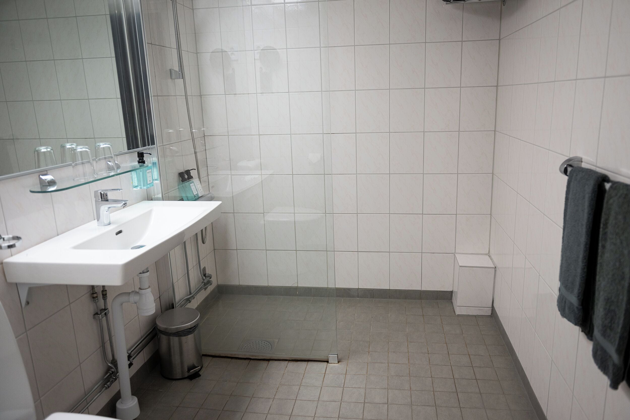 A bathroom with a white sink, mirror, and tiled walls.