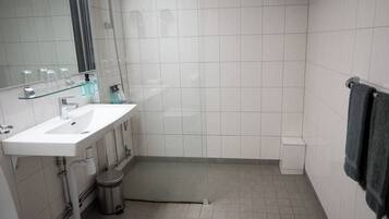A bathroom with a white sink, mirror, and tiled walls.
