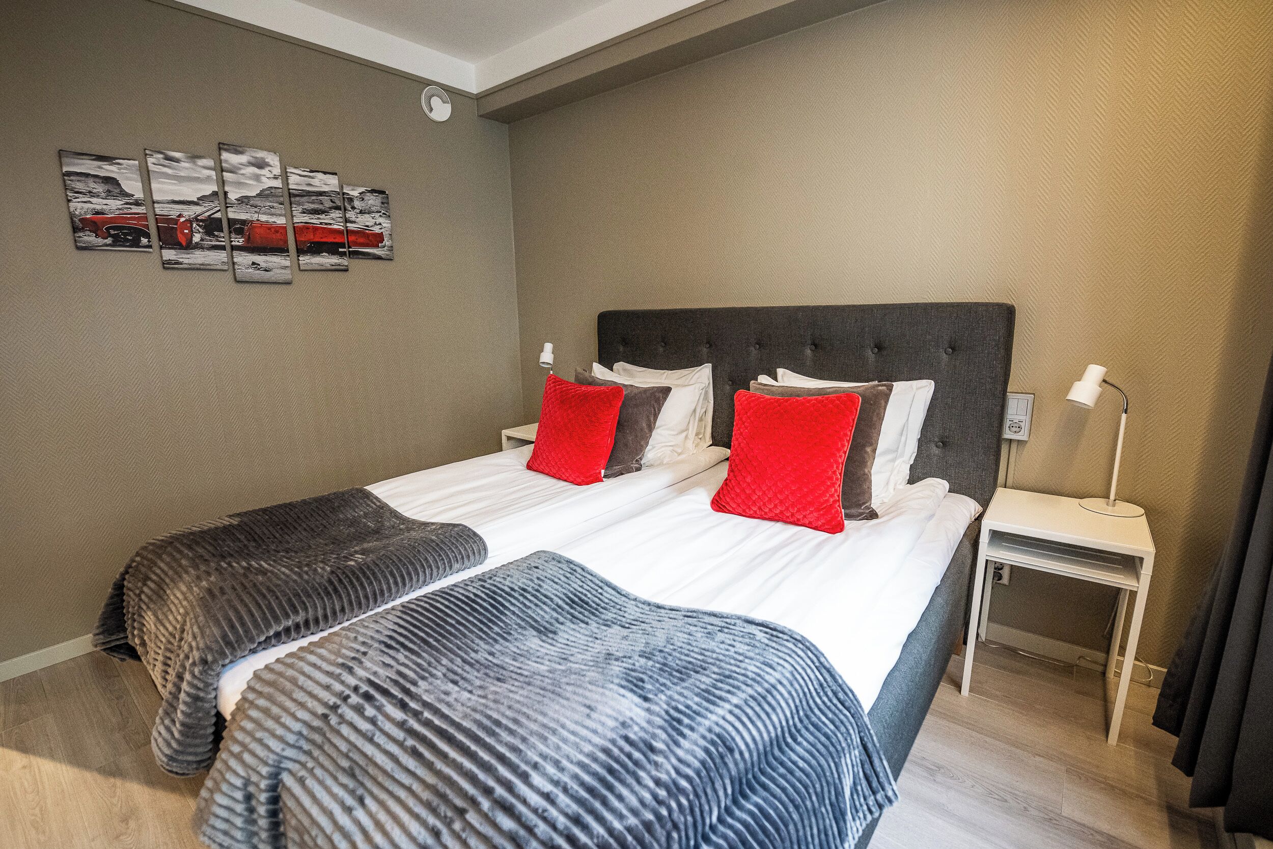 Habitación de hotel con una cama grande, dos mesitas de noche, una lámpara de pared y un cuadro en la pared.