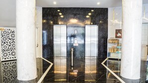 A modern elevator with a black marble wall and a metallic handrail. - 7s Hotel An Phú Central (Ho Chi Minh City)