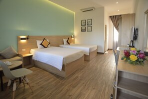 A hotel room with two beds, a desk with a chair, a small table with cups, and a flower arrangement. - 7s Hotel An Phú Central (Ho Chi Minh City)