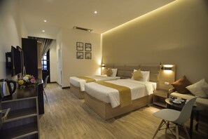 A hotel room with two beds, a desk, a chair, and a small table with cups and a teapot. - 7s Hotel An Phú Central (Ho Chi Minh City)